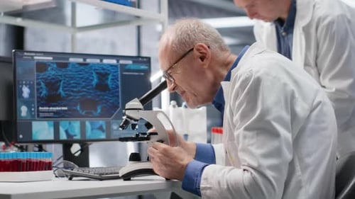 Laboratório com velho cientista masculino observando espécimes sob microscópio