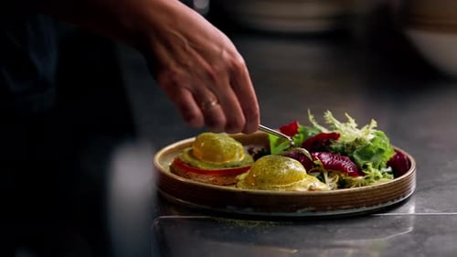 Close Up in a Professional Kitchen on Clean Metal Table a Woman Chef Collects a Salad with Fresh