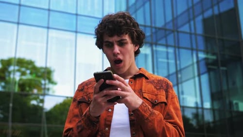 Young Adult Triumph with Smartphone in Urban Setting