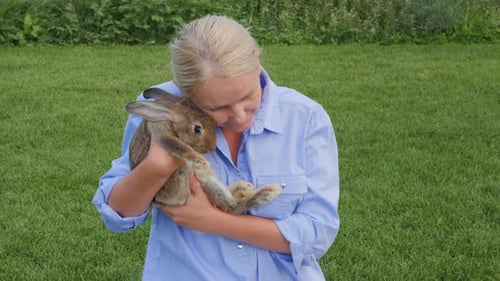 A Woman Holds Her Cute Rabbit in Her Arms Cradling It Gently Like a Baby During a Walk with Her