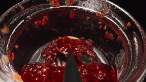 A jar of raspberry jam, spoon in the jar. Dolly slider extreme close-up inside. Laowa Probe