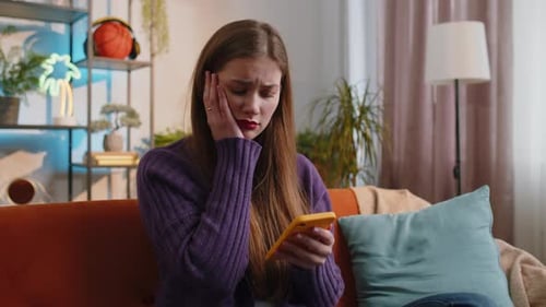 Upset Woman Using Mobile Phone on Sofa