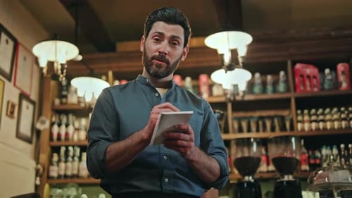 Charismatic Waiter Using Pen and Notes While Servicing Customers at Bar