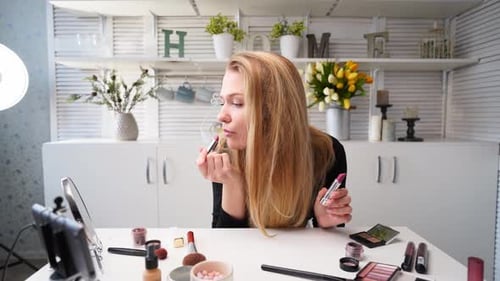Mujer vloguera aplica lápiz labial en los labios, bloguera de belleza, mujer filmando una rutina diaria de maquillaje, tutorial