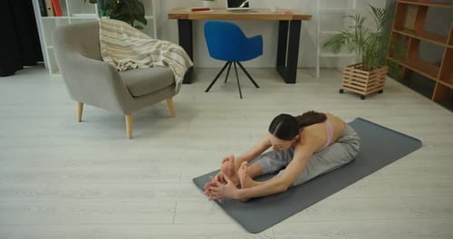Young Woman Stretching Forward on Yoga Mat Indoors