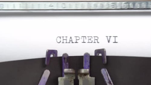 Chapitre Six : gros plan d'une phrase en cours de saisie et centré sur une feuille de papier sur une vieille machine à écrire vintage