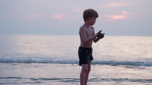 Young Boy Playing with Sand at Beach Sunset