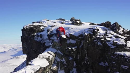 High-alpine scrambling from a knife edged ridge up to an exposed peak
