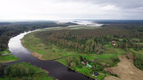 Beautiful aerial drone footage of a winding river in the foreground with a lake in the background.