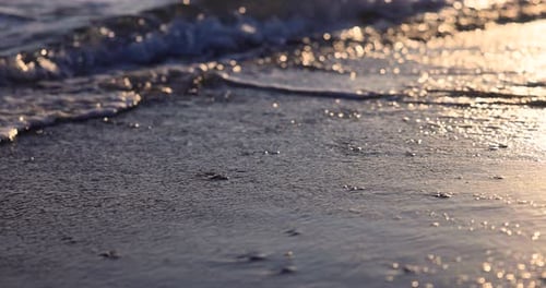 Woman's legs walking on the sea waves against the sunset during summer vacation. Slow motion