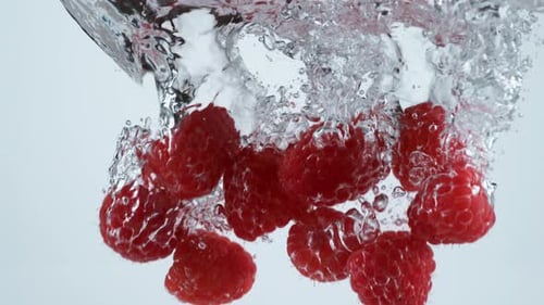 Vibrant Raspberries Plunging into Refreshing Water