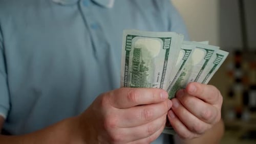 Close-up of a young man's hands counting hundred dollar bills.