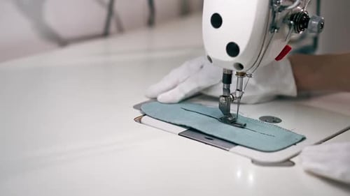 Nettoyeur à sec professionnel Glose Up, jeune fille, ourle un patch sur un pull à l'aide d'une machine à coudre