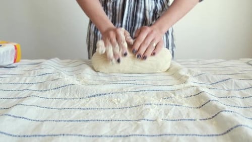 Woman Kneading Dough on Striped Tablecloth