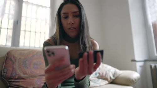 Woman using smartphone to buy a product online adding credit card information while sitting at home