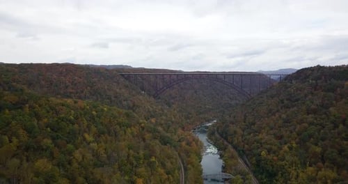 Aerial dolly shot toward the River Gorge Bridge with an autumnal forest surrounding