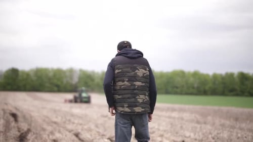 farmer watching his tractor planting sunflower at the field
