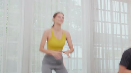 Woman and Man Doing Jumping Jacks Together Indoors