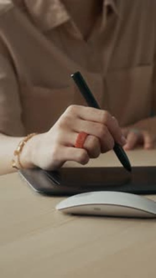 Hand Uses Stylus on Tablet in Workplace