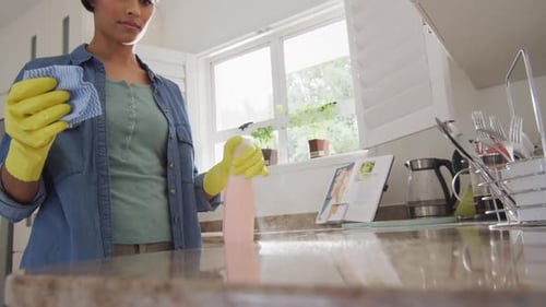 Vídeo de una mujer birracial feliz limpiando la cocina
