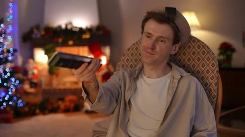 Bored Lonely LGBT Man Switching Channels with Remote Control Sitting in Rocking Chair in Living Room