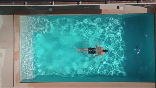 Luftaufnahme eines Mannes, der im klaren blauen Pool schwimmt