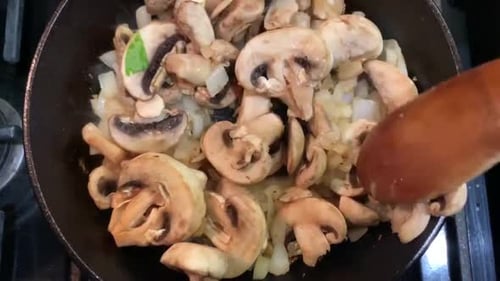 Cooking mushrooms and onions over a cast iron skillet. Healthy, nutritious, food video. Overhead vie