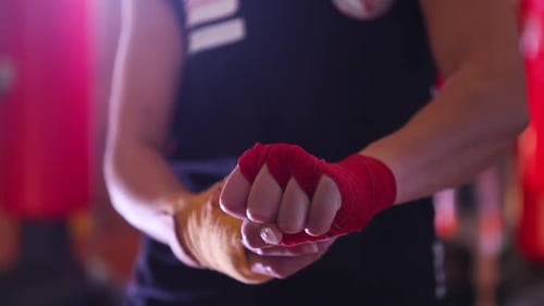 Detail view of professional female boxer wrapping hands with yellow and red protective band for trai