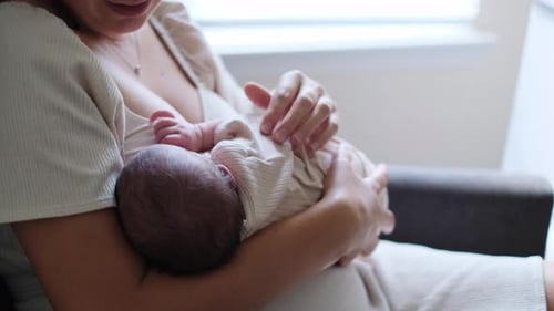 Mother breastfeeding her newborn infant at home