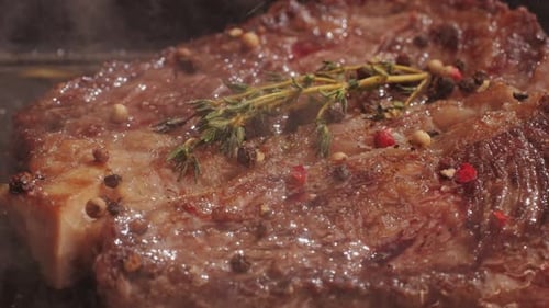 Fresh Marbled Beef with Pepper Salt and Rosemary Closeup Macro Cooking Juicy Steak on Grill with Oil