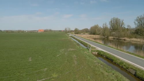 Aerial view of cyclists ride on paved road on sunny day, Netherlands
