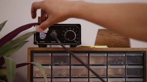 Un hombre enciende y afina una bordeadora eléctrica de cuero en el taller