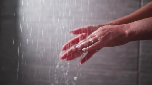 Woman's Hands Under Shower Water in Bathroom