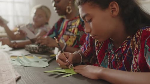 Girl Drawing on Paper with Family Indoors