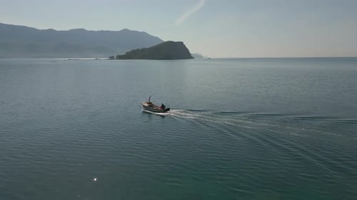 A fisherman is sailing in a boat on the sea. Flying a drone over a fishing boat.