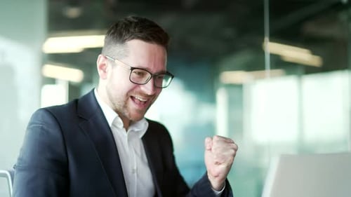 Close up. Excited happy businessman in formal suit received great news on laptop sitting