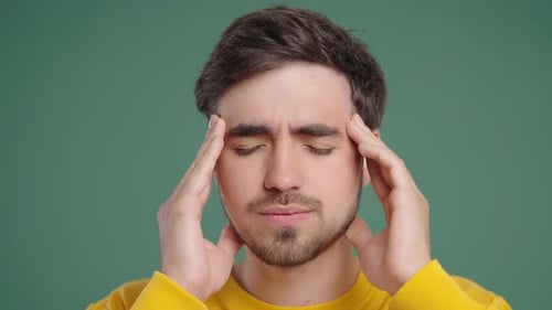 20S Aged Man Having Headache Touching Temples Suffering On Green Background
