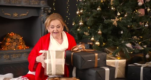 Senior Woman Arranging Christmas Presents by Christmas Tree