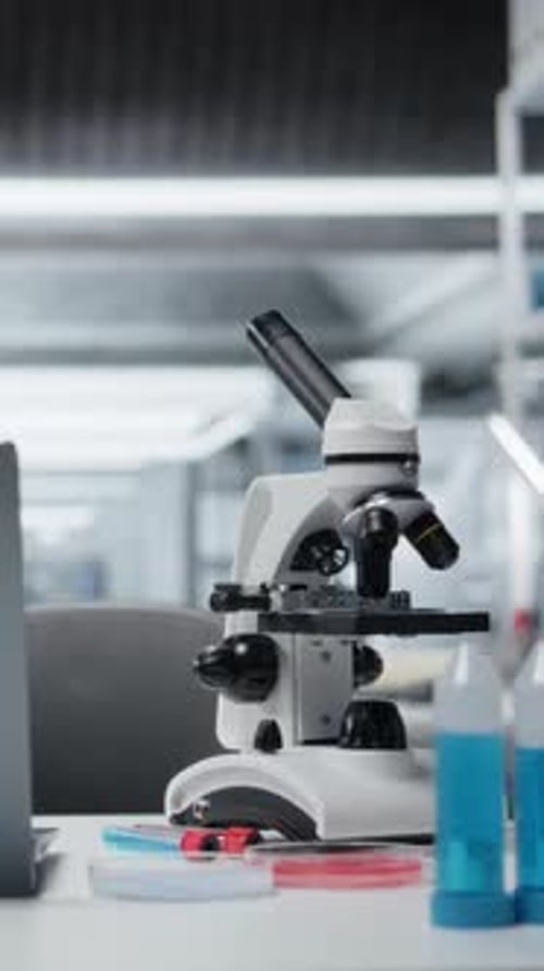 Vertical Video Close Up of Laptop on Laboratory Workbench Next to Microscope and Samples