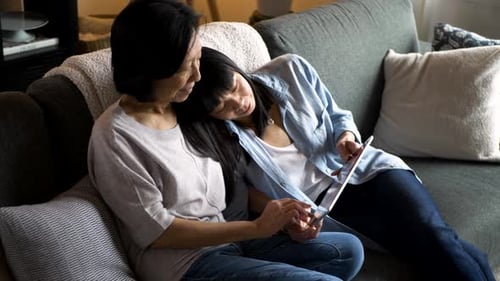 Relaxing women use tablet together on a couch