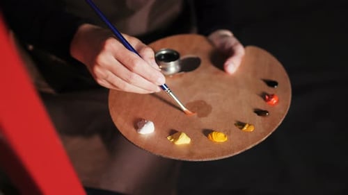 Artist Mixing Paint Colors on Palette with Brush