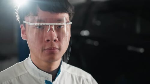 CloseUp of Chinese Student Adjusting Protective Glass in Illuminated Workshop