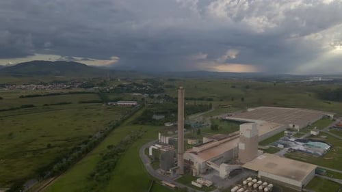 Aerial View of Midsize Factory with Dramatic Skies and Surrounding Greenery