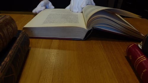 Man's hands leafing through an old book in the library
