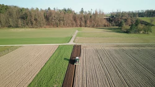 Aerial view of farming tractor plowing agriculture field in spring
