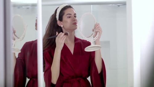 Woman Applies Makeup Using Handheld Mirror