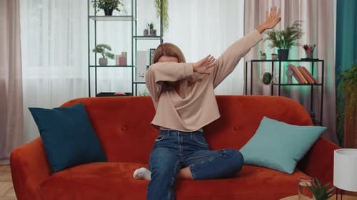 Woman Dancing and Smiling on Couch in Home Interior