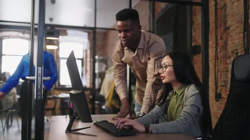 Journée de travail active au bureau : personnes multiethniques travaillant avec un ordinateur, discutant de projets et marchant