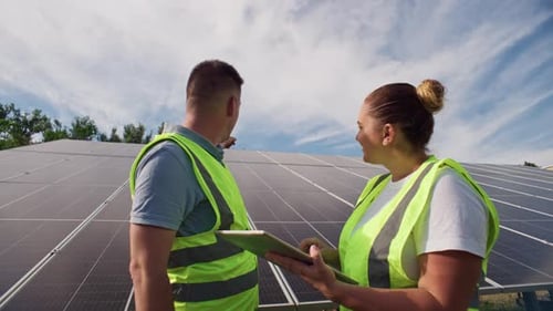 Two Engineers Discussing Solar Energy Production Tablet Control of Solar Panels