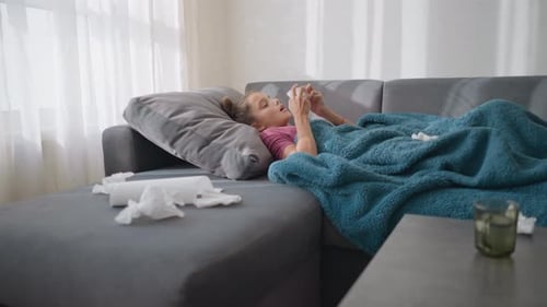 Child Resting Under Blanket Wiping Nose